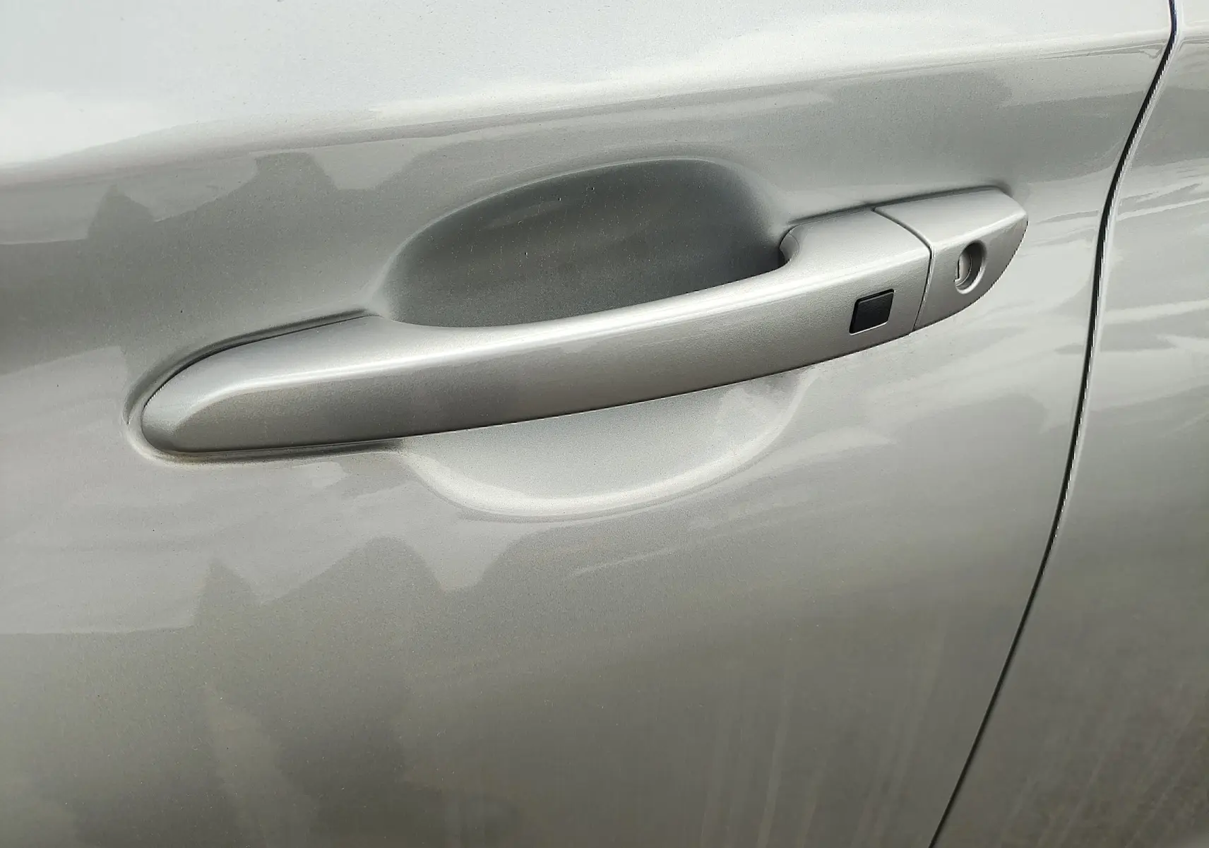 Poignée de porte côté gauche gris métallisé sur Hyundai Kona Electric 2025, avec bouton de déverrouillage.