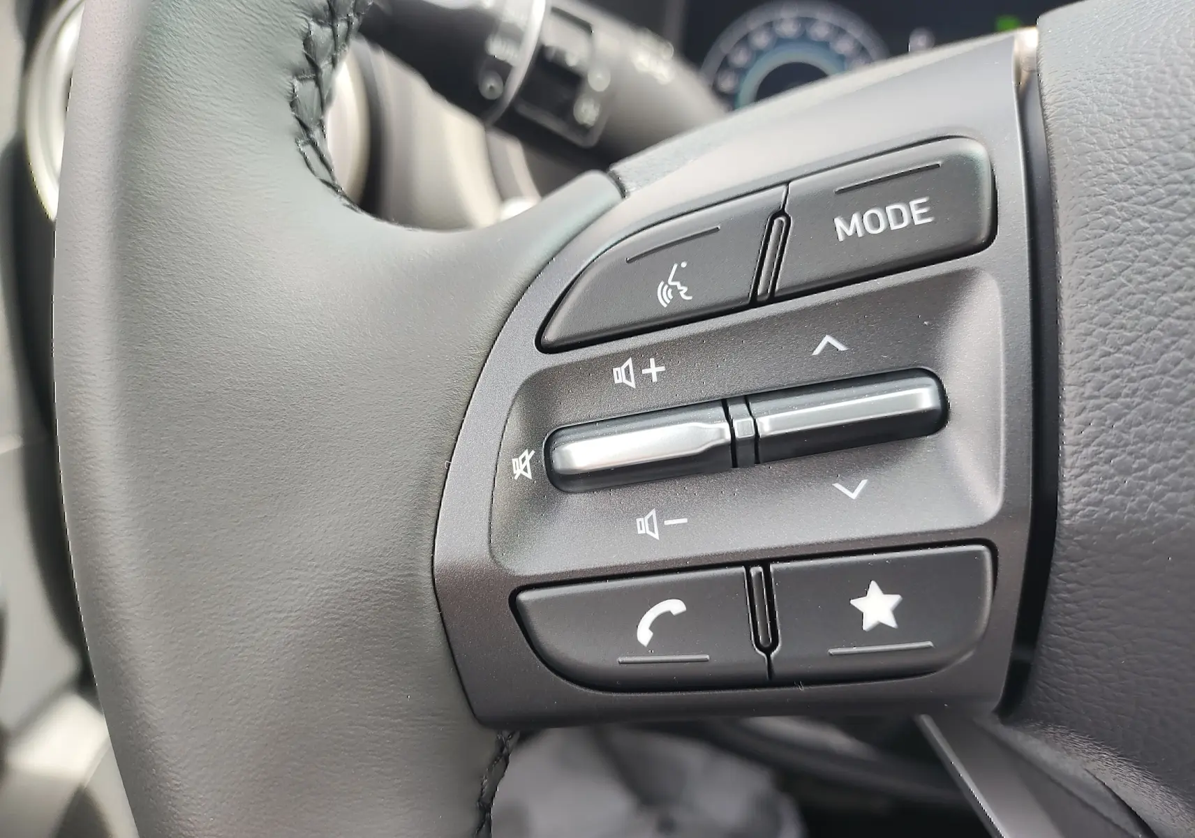 Gros plan sur les commandes audio au volant cuir noir d'une Hyundai Kona Electric 2025, côté gauche.