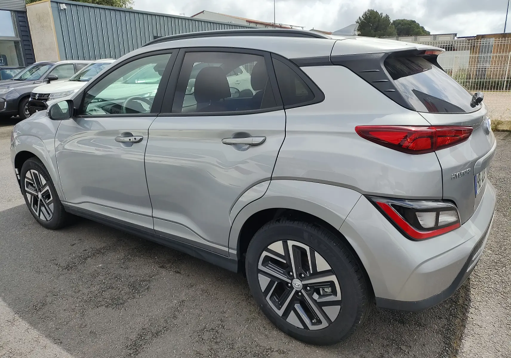 Vue 3/4 arrière côté droit d'un Hyundai Kona électrique gris métallisé avec jantes alliage et vitres surteintées.