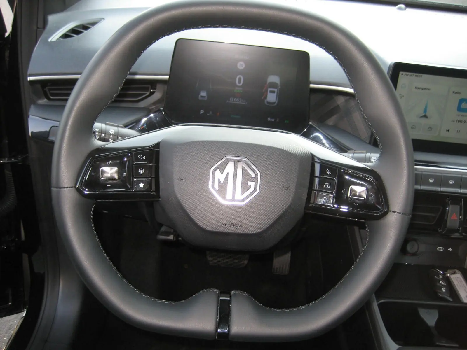 Vue rapprochée du volant noir du MG3 2024 avec commandes intégrées et tableau de bord numérique en arrière-plan.