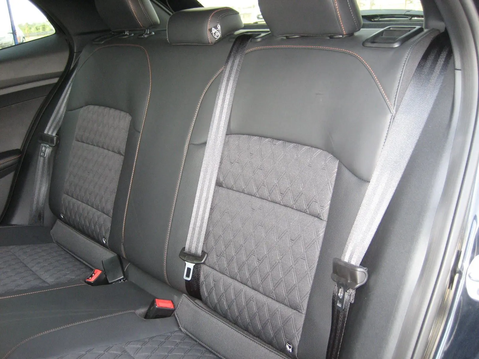 Vue rapprochée des sièges arrière noirs du MG3 2024 avec surpiqûres orange et ceintures de sécurité grises.