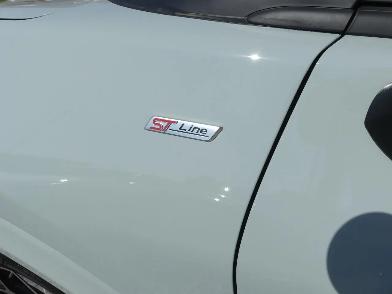 Gros plan sur l'écusson ST-Line sur la porte côté gauche d'un Ford Puma gris métallisé 2025.