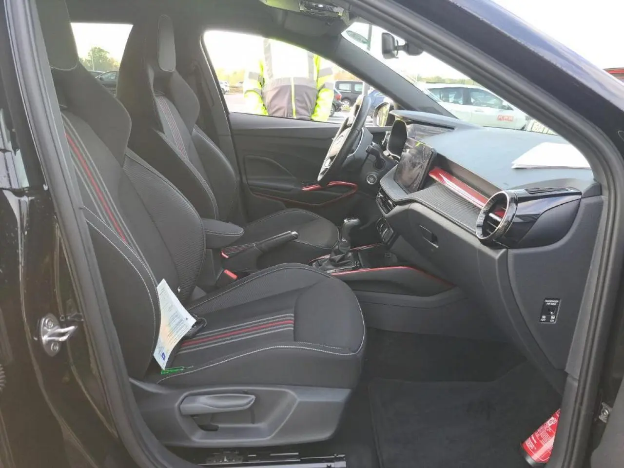 Vue intérieure côté gauche de la Skoda Fabia Monte Carlo 2024 avec sièges noirs à bandes rouges et tableau de bord moderne.