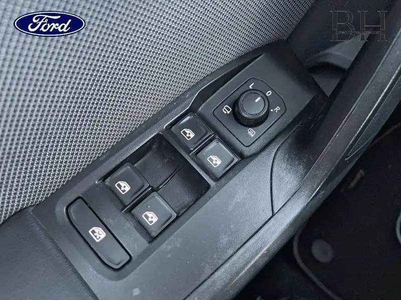 Gros plan sur les commandes de lève-vitres et rétroviseurs côté conducteur d'une SEAT LEON ST gris urbain métal.