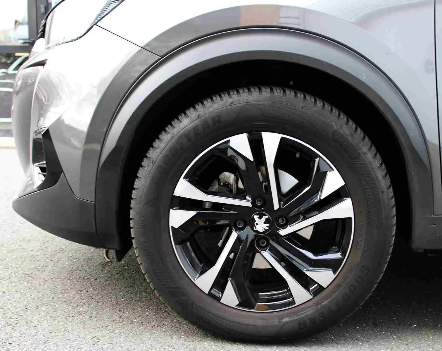 Gros plan sur la roue avant droite du Peugeot 2008 gris platinium, mettant en valeur la jante noire et argentée au design moderne.