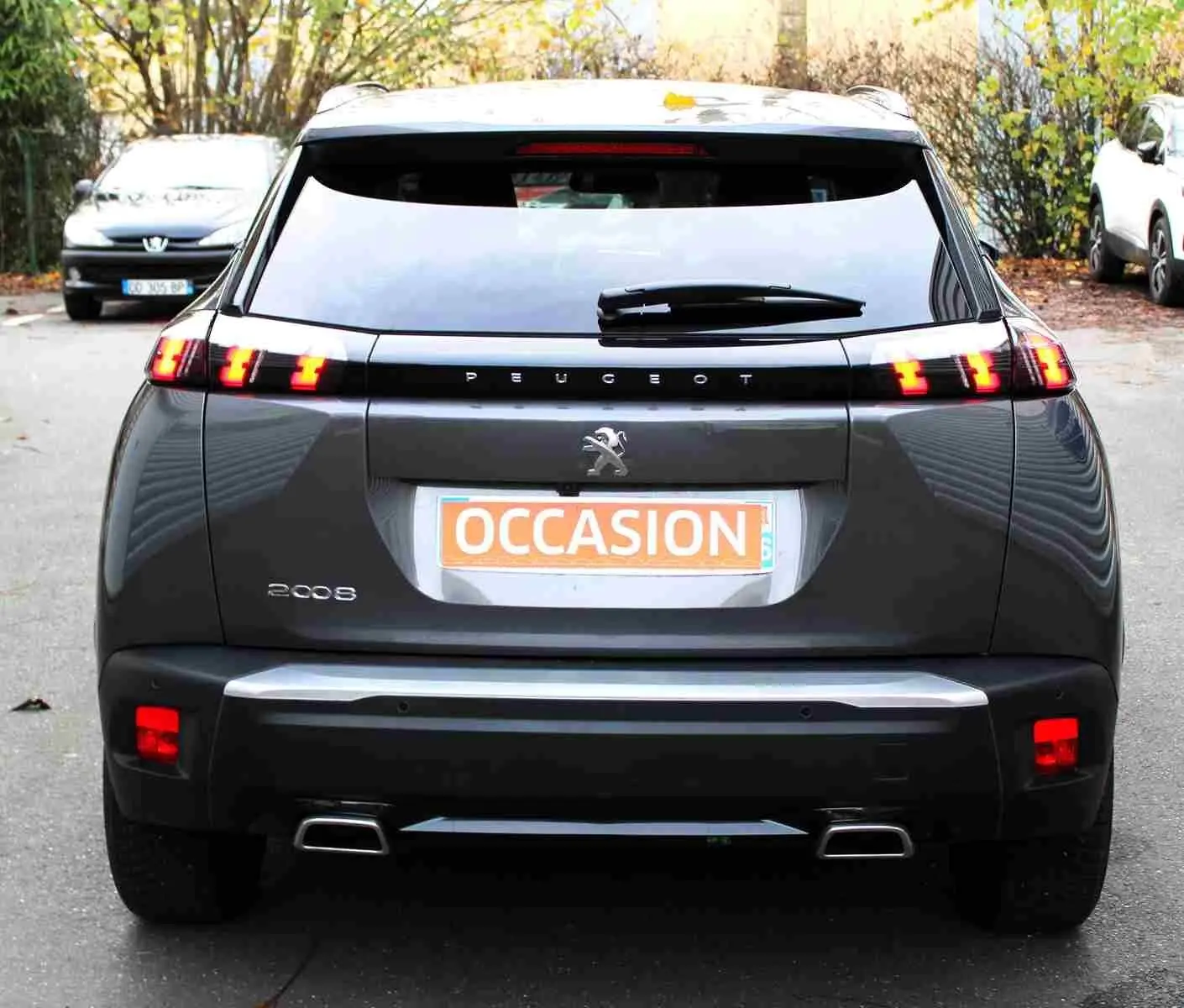 Vue arrière d'un Peugeot 2008 gris platinium avec feux arrière allumés et plaque d'occasion visible