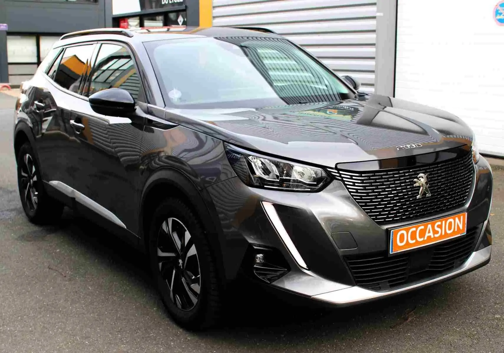 Peugeot 2008 gris platinium en 3/4 avant droit avec calandre noire et plaque "OCCASION" visible.
