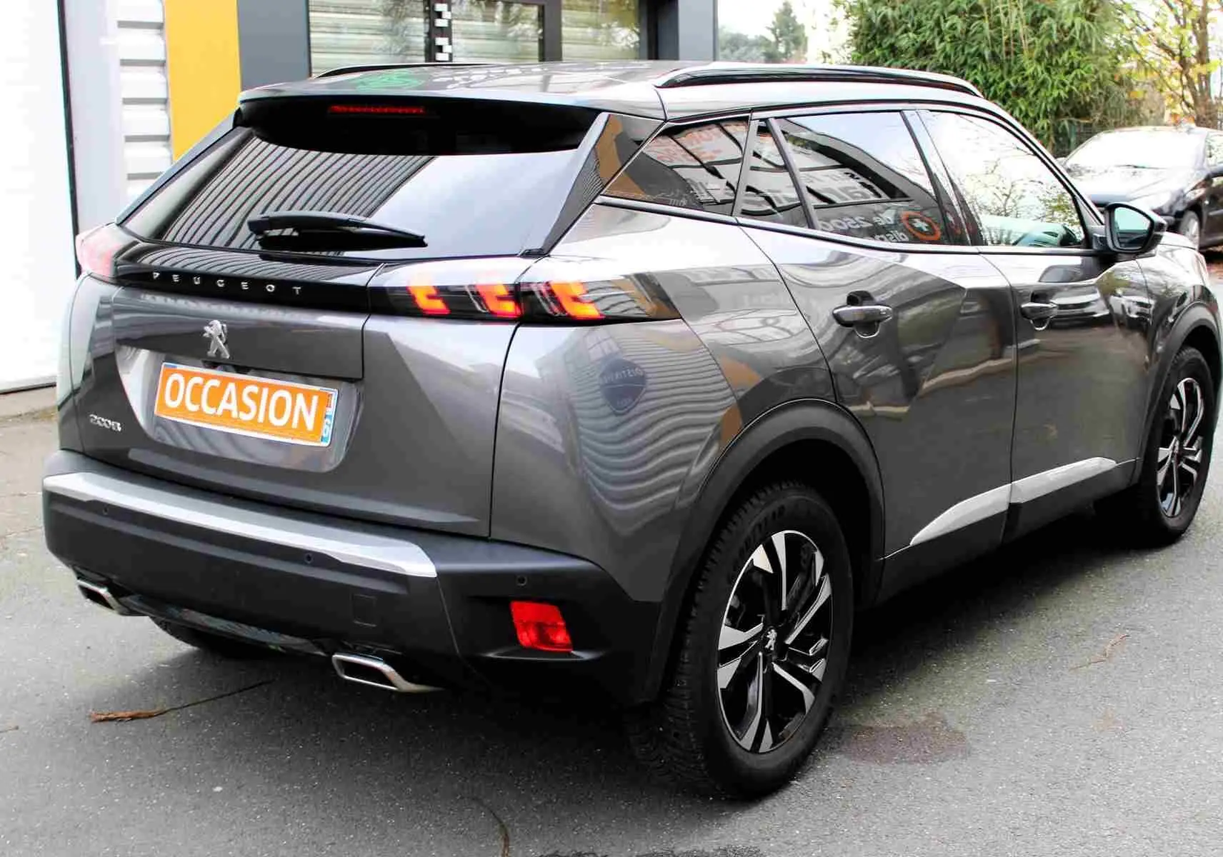 Vue 3/4 arrière droite d'un Peugeot 2008 gris platinium avec feux arrière LED et jantes alliage bicolores.