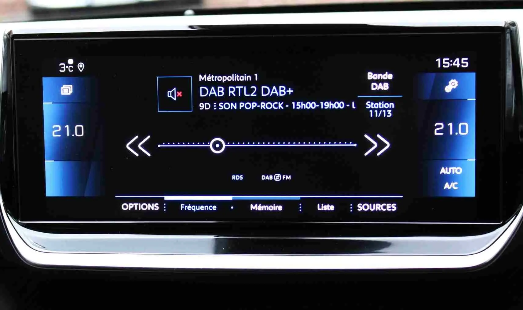 Écran tactile central du tableau de bord du Peugeot 2008 gris platinium affichant la radio DAB et la climatisation à 21°C.