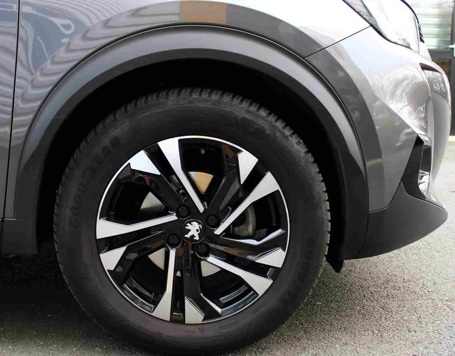 Gros plan sur la roue avant gauche du Peugeot 2008 gris platinium avec jante alliage bicolore au design moderne.