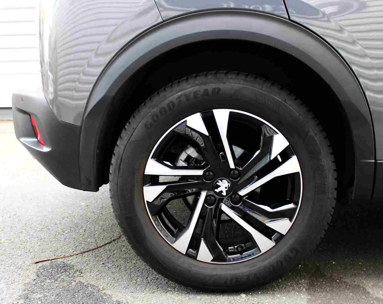 Gros plan sur la roue arrière droite d’un Peugeot 2008 gris platinium avec jante alliage bicolore et pneu Goodyear.