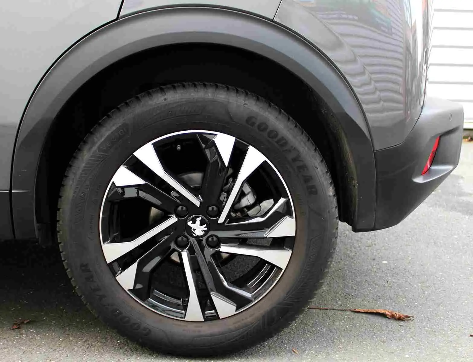 Gros plan sur la roue arrière droite du Peugeot 2008 gris platinium avec jante alliage bicolore et logo lion central.