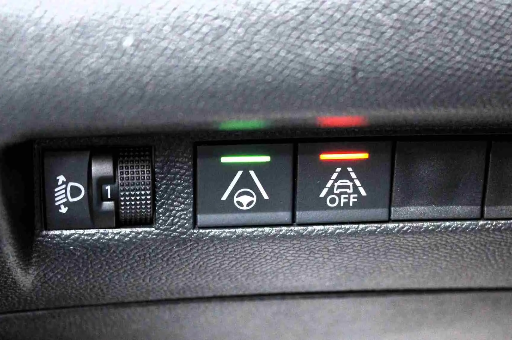 Gros plan sur les commandes d'assistance à la conduite avec voyants vert et rouge dans l'habitacle d'un Peugeot 2008 gris platinium.