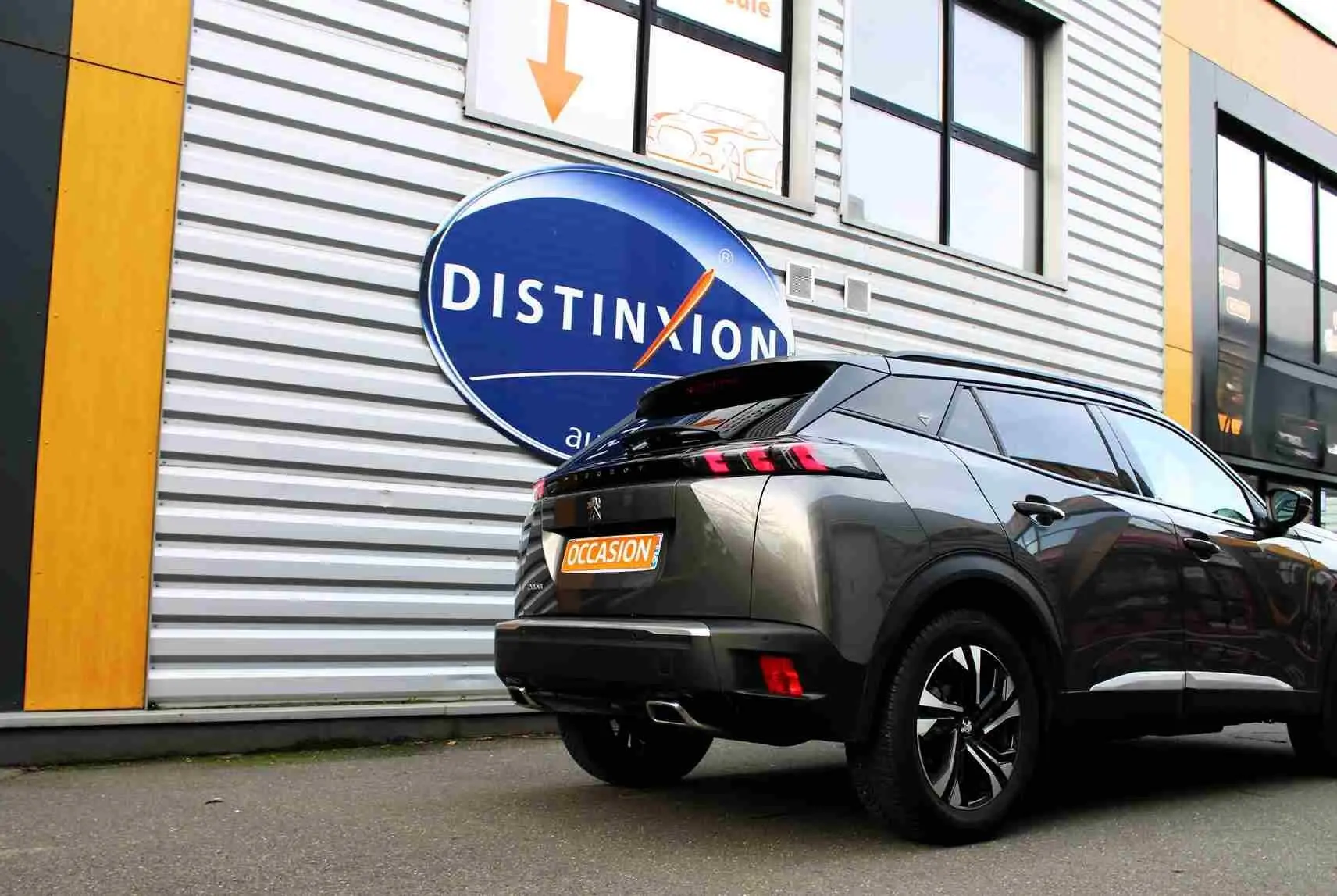 Peugeot 2008 gris platinium en 3/4 arrière droit, avec feux arrière à griffes et jantes noires bicolores.