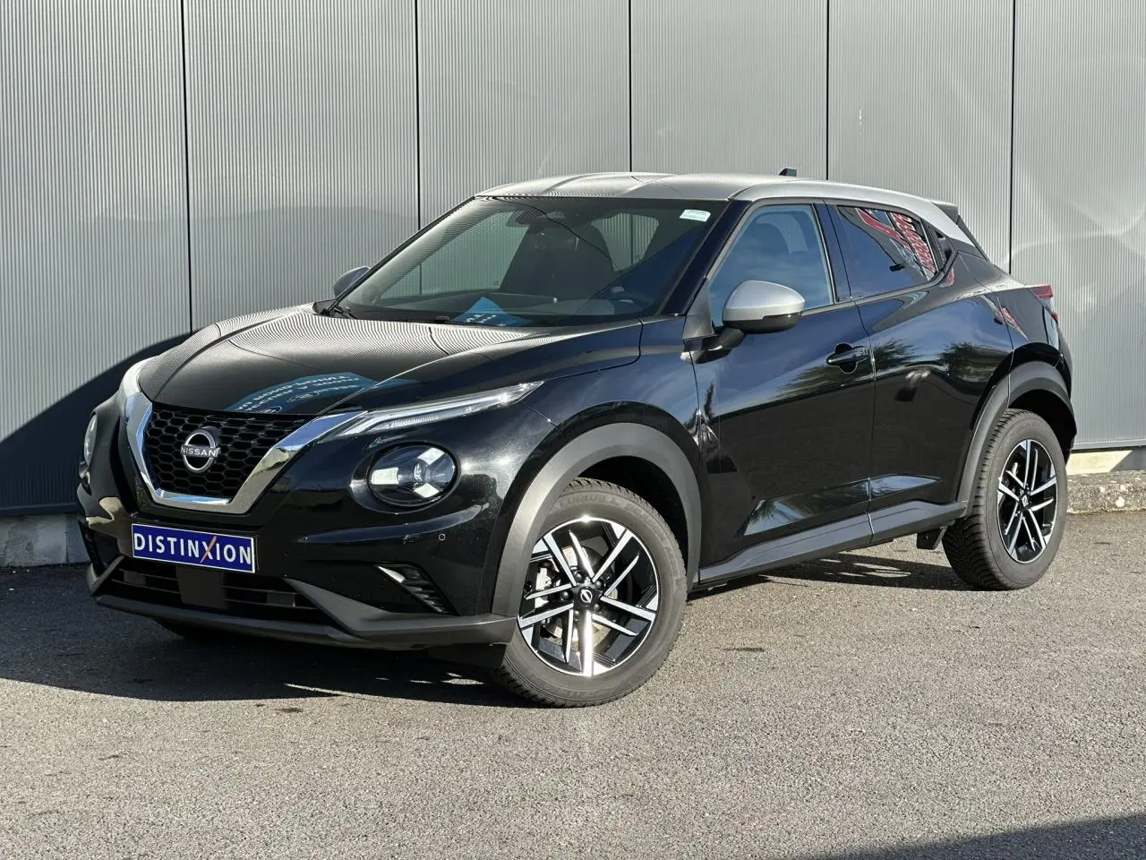 Nissan Juke noir métallisé en 3/4 avant droit, avec jantes alliage 17'' et calandre chromée distinctive.