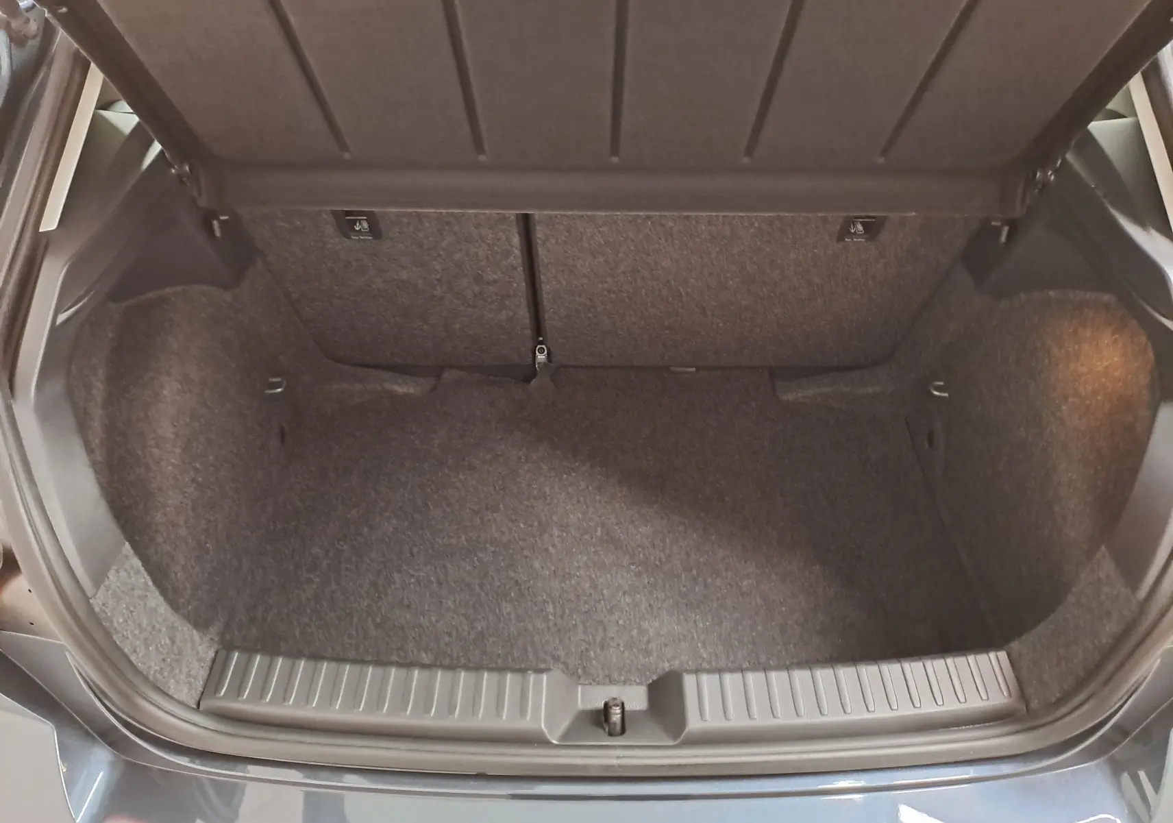 Coffre ouvert vu de dessus d’une SEAT IBIZA gris magnétique, montrant l’espace de rangement intérieur vide.