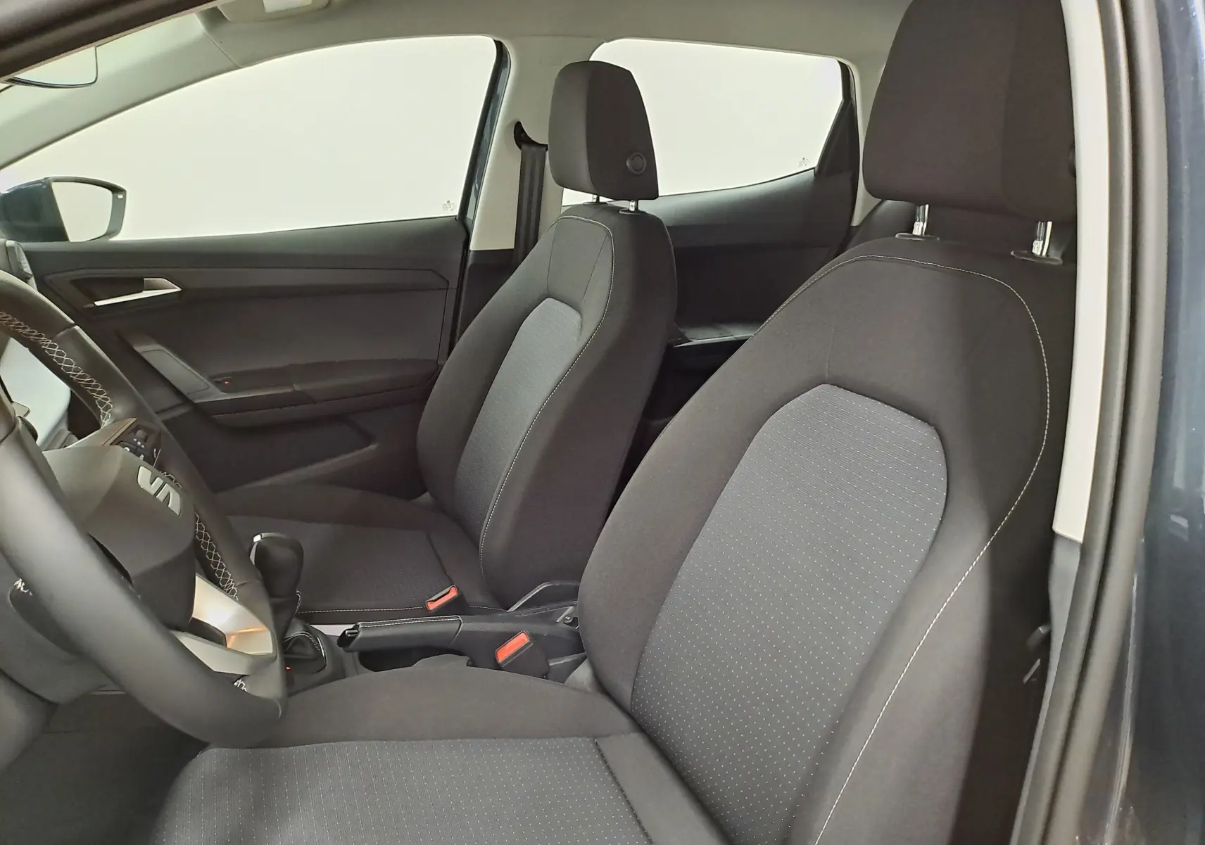 Vue intérieure côté gauche montrant les sièges avant en tissu gris foncé de la SEAT IBIZA 2025 gris magnétique.