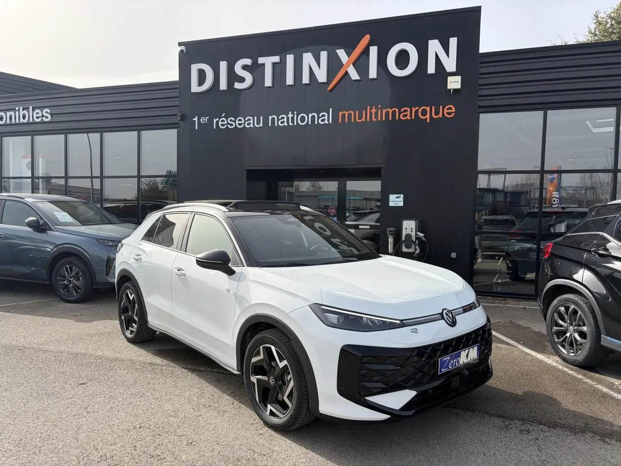 Volkswagen T-Roc blanc pur toit noir en 3/4 avant droit, avec jantes noires et calandre noire distinctive.