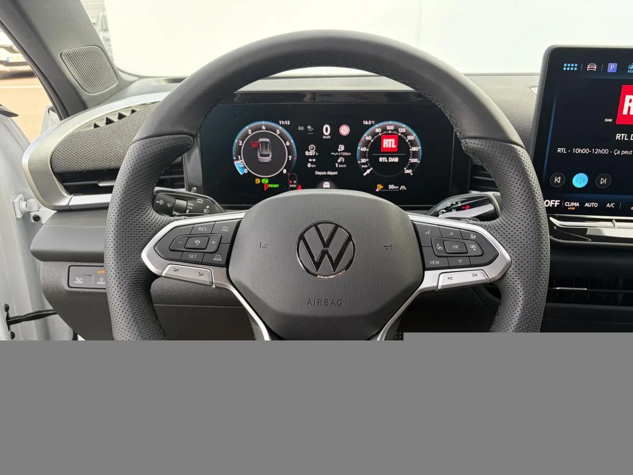 Vue rapprochée du volant multifonction en cuir noir du Volkswagen T-Roc avec tableau de bord numérique et écran central tactile.