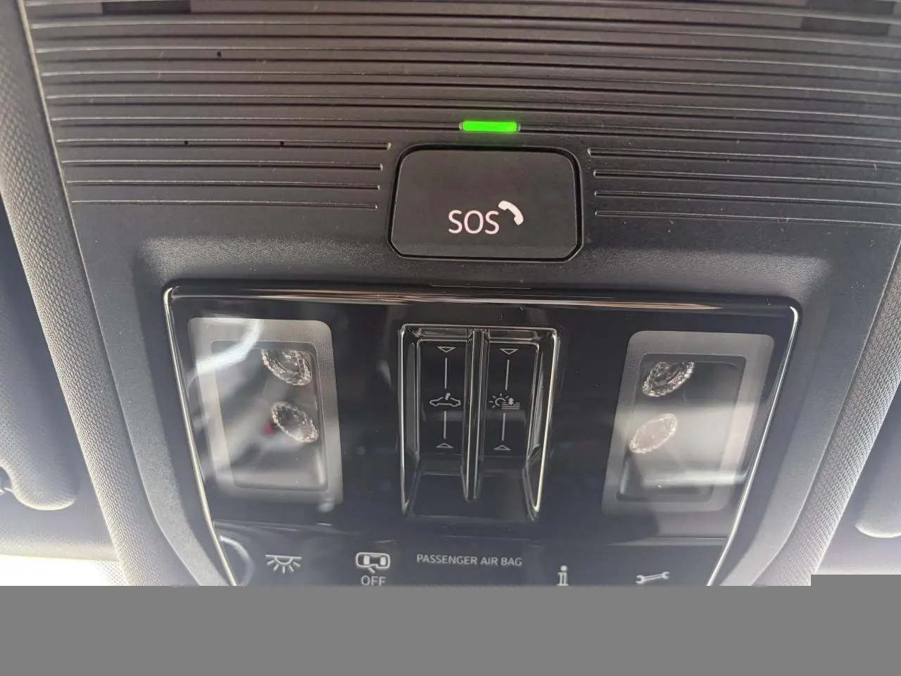 Vue rapprochée du panneau de commande intérieur au plafond du Volkswagen T-Roc blanc, avec bouton SOS et commandes d’éclairage.
