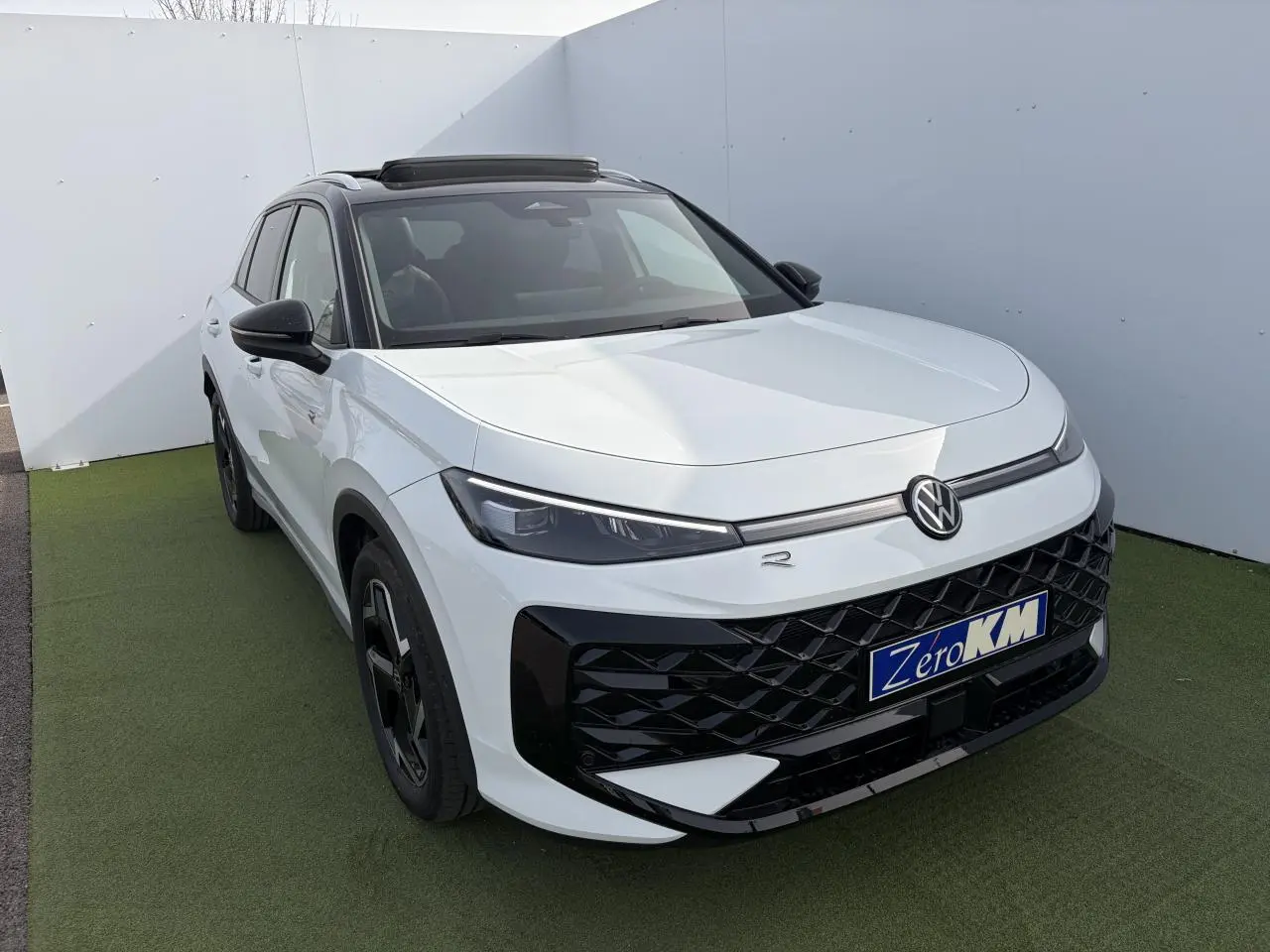 Volkswagen T-Roc blanc pur toit noir en vue 3/4 avant droit avec calandre noire et jantes noires distinctives.