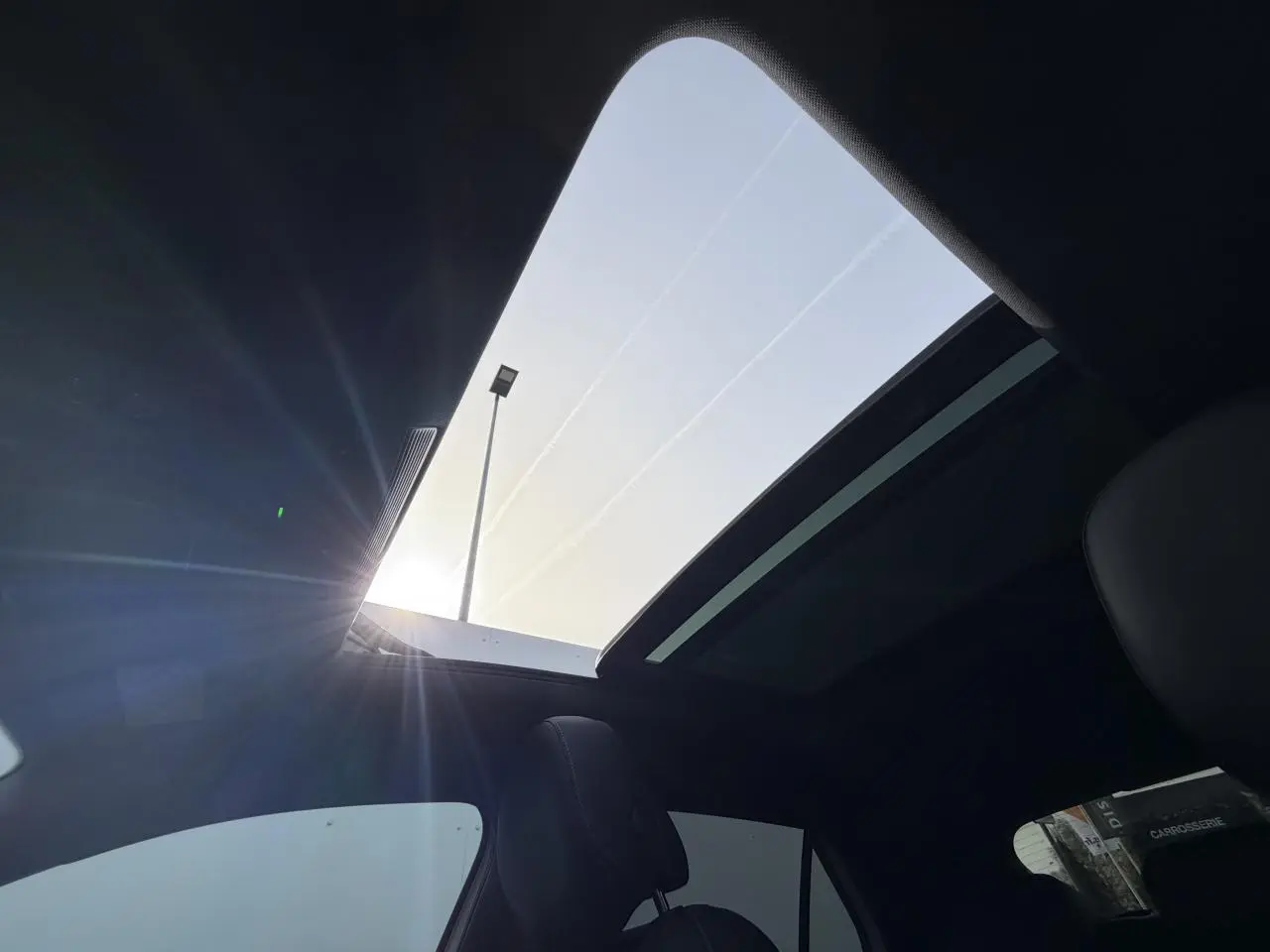 Vue intérieure du toit ouvrant panoramique du Volkswagen T-Roc blanc pur avec ciel de pavillon noir, lumière naturelle entrant par le toit.