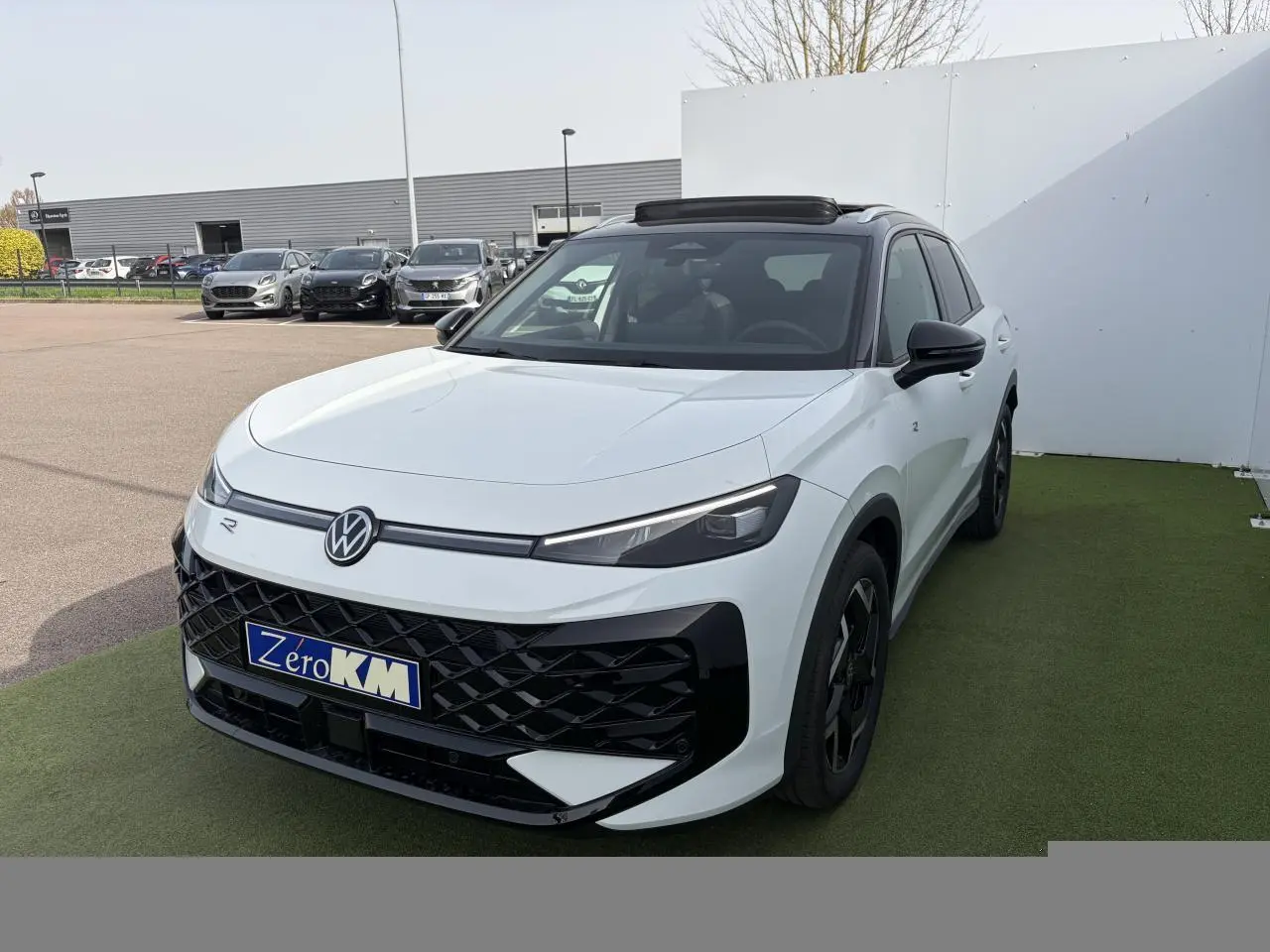 Volkswagen T-Roc blanc pur avec toit noir, vue 3/4 avant droit, calandre et jantes noires distinctives.