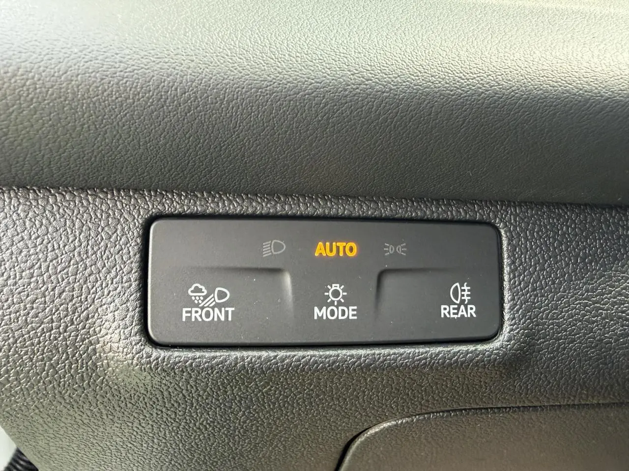 Panneau de commande d'éclairage automatique avec mode auto activé dans un Volkswagen T-Roc blanc toit noir.