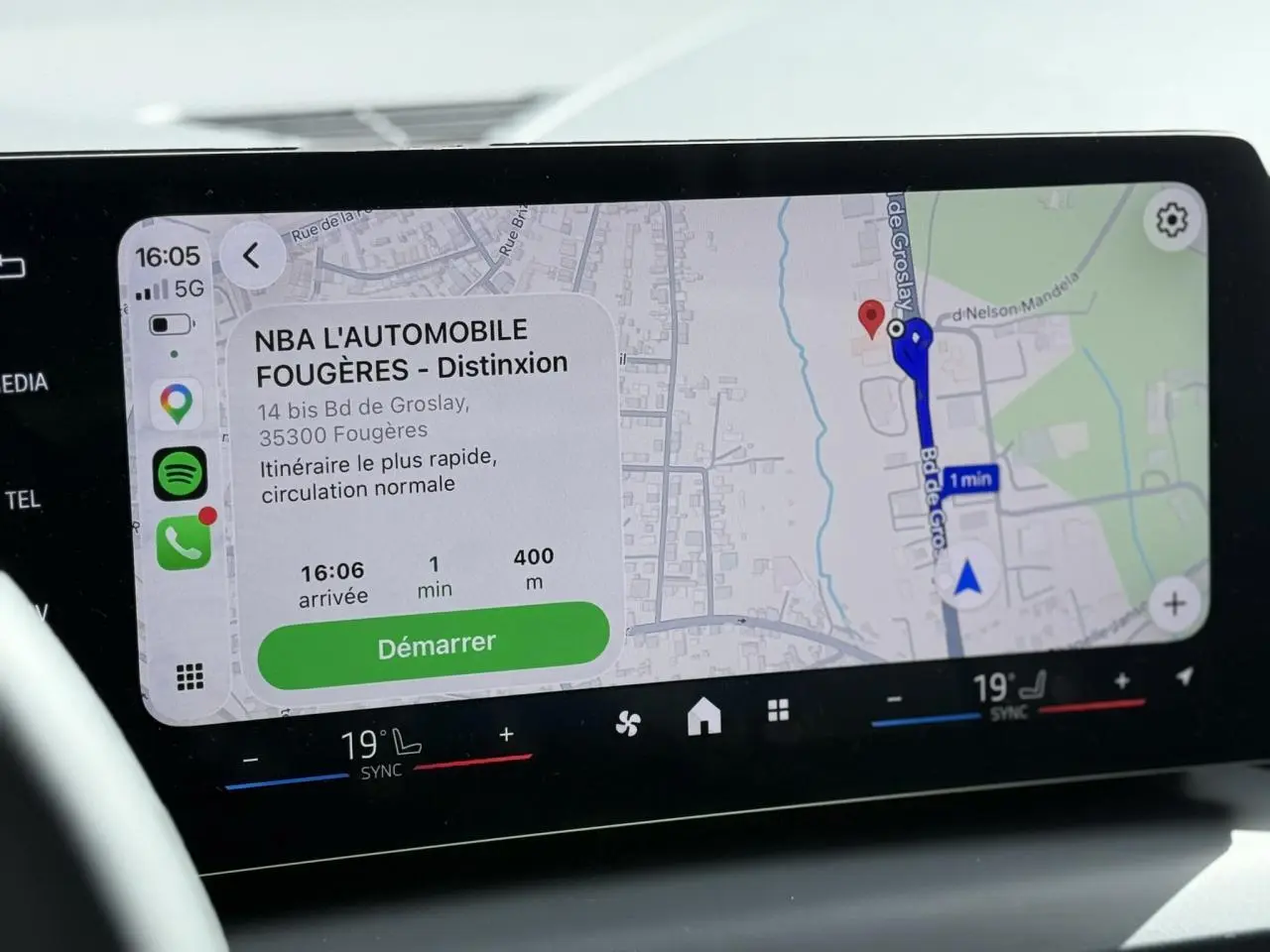 Écran tactile du système de navigation BMW Live Cockpit affichant un itinéraire avec commandes climatisation bi-zone en dessous.