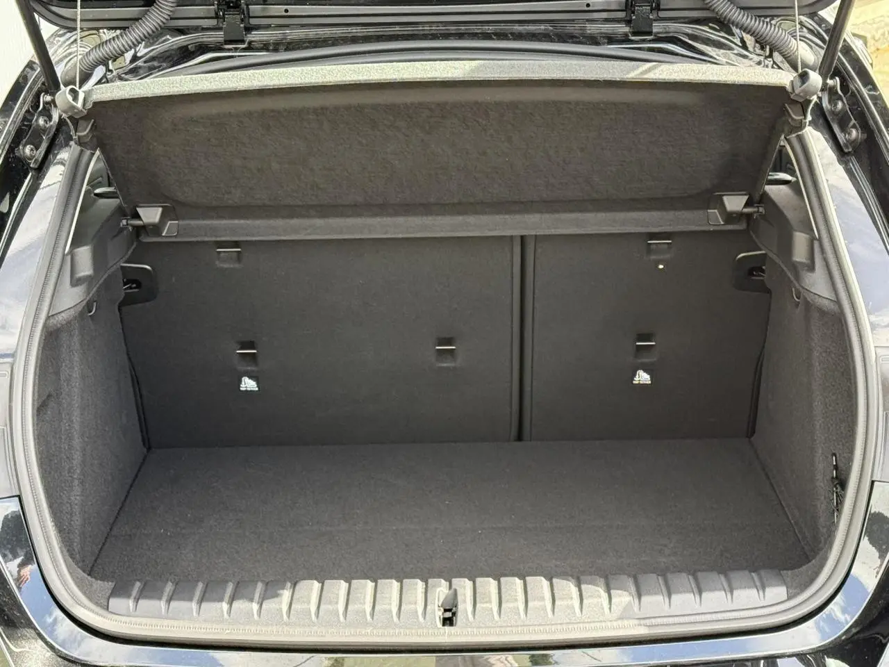 Coffre ouvert vu de l'arrière d'une BMW Série 1 F70 118dA M Sport en noir Saphirschwarz, intérieur tissu anthracite.
