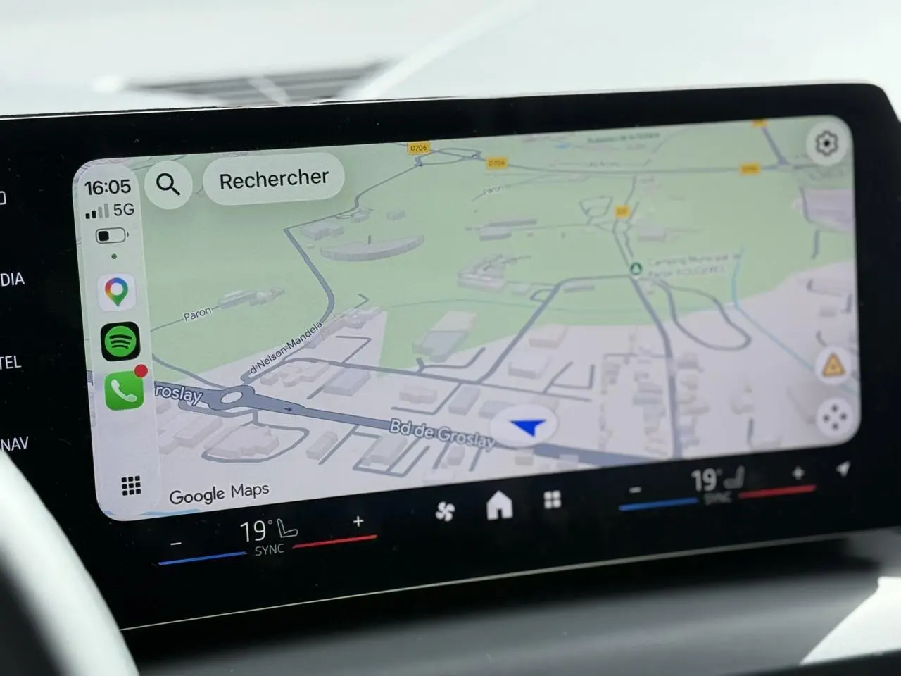 Écran tactile BMW Curved Display affichant la navigation Google Maps et commandes climatisation bi-zone.