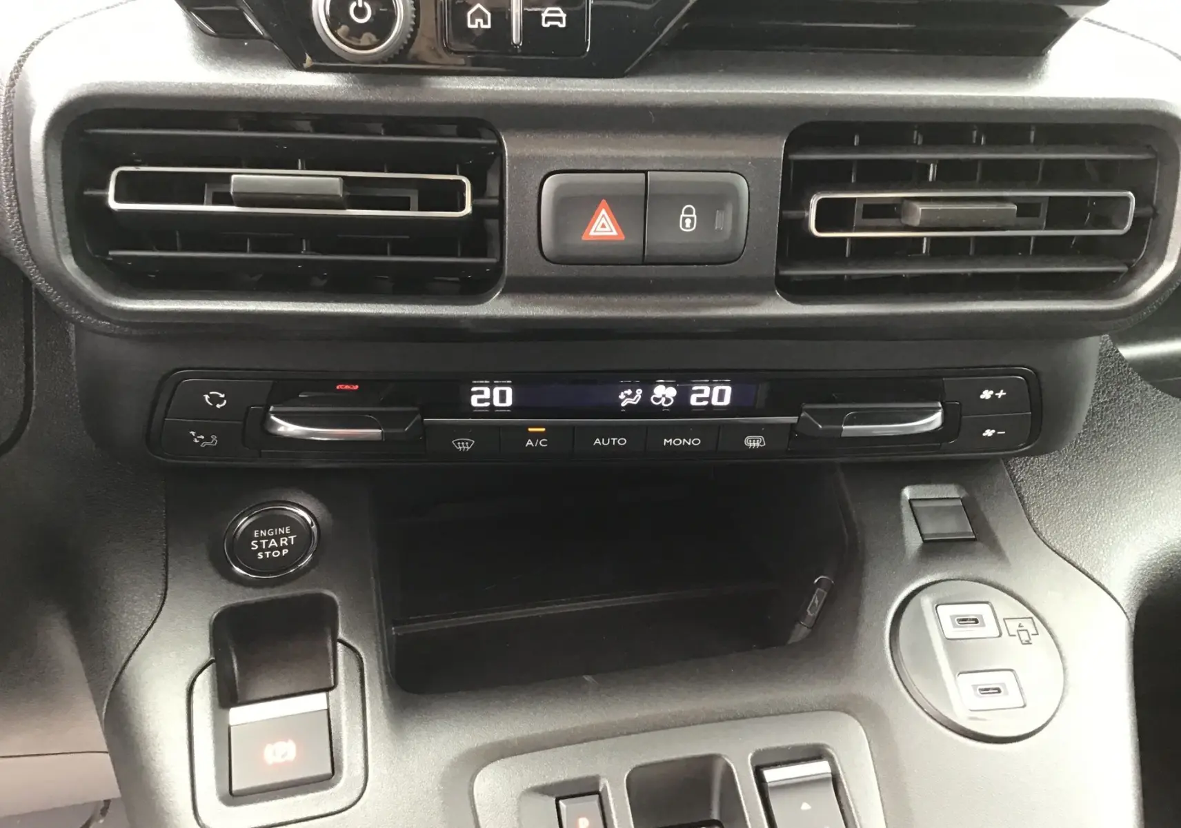 Vue rapprochée du tableau de bord du Peugeot Partner blanc 2026, montrant la climatisation digitale et le bouton start/stop.