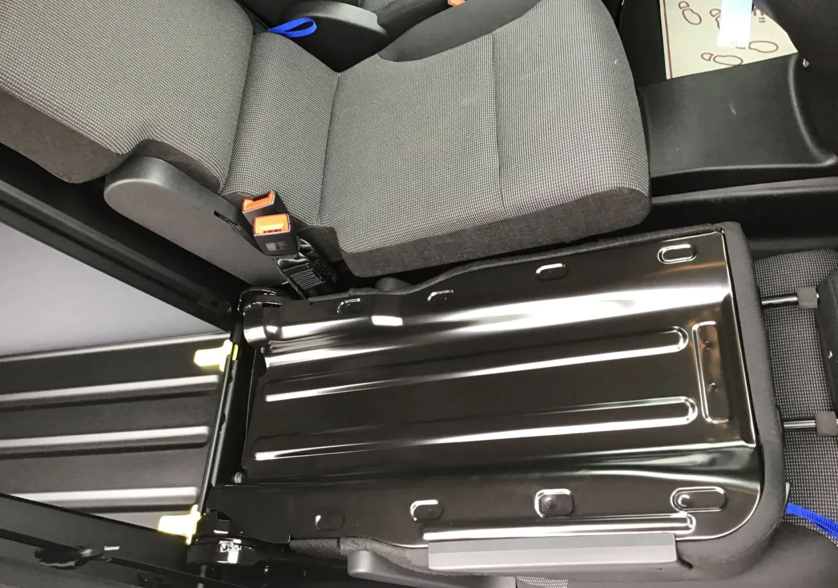 Vue rapprochée de la banquette arrière rabattue du Peugeot Partner XL blanc, montrant le plancher métallique et les sièges gris.