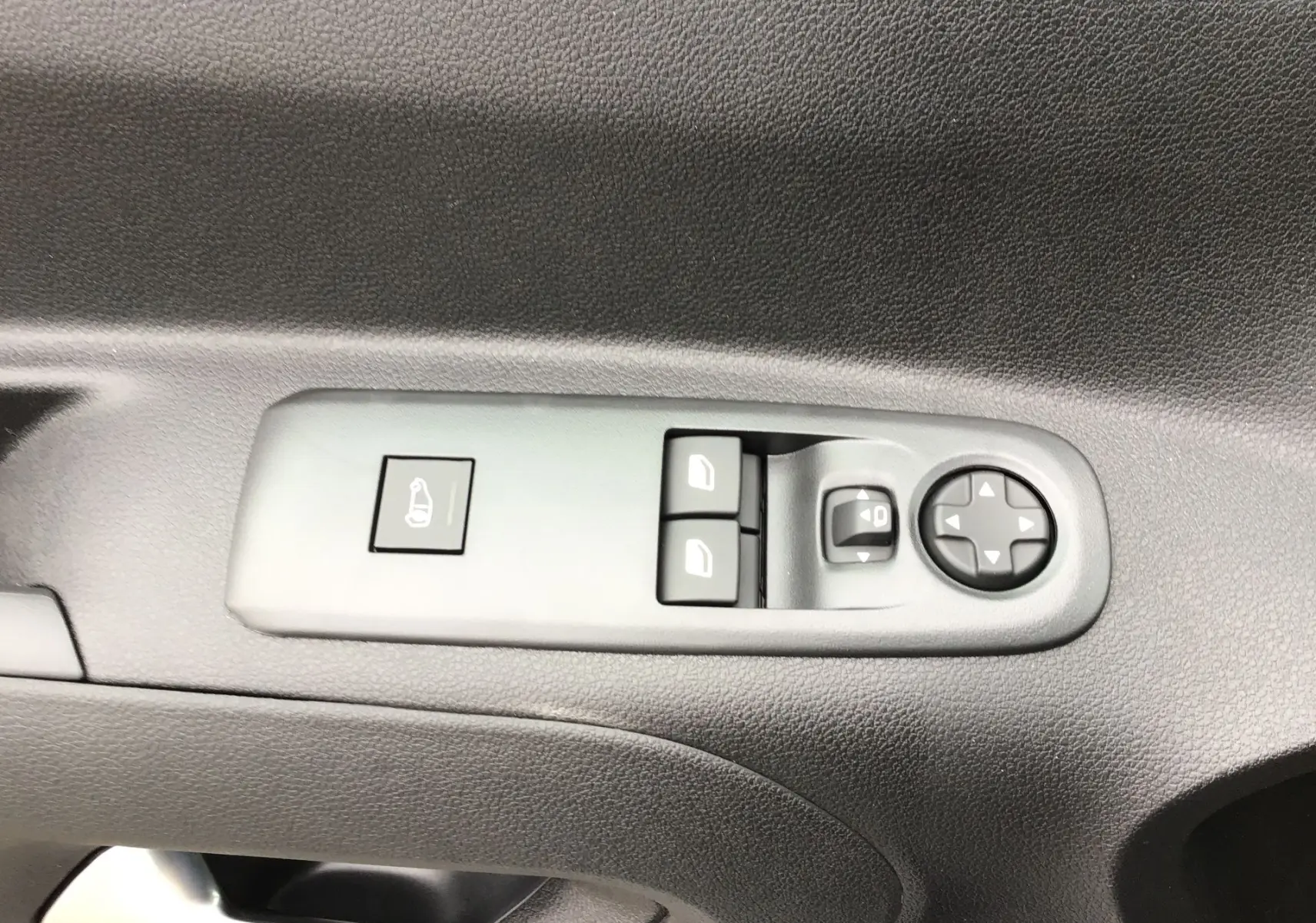 Gros plan sur les commandes de lève-vitres et rétroviseurs électriques sur la porte intérieure d’un Peugeot Partner blanc.