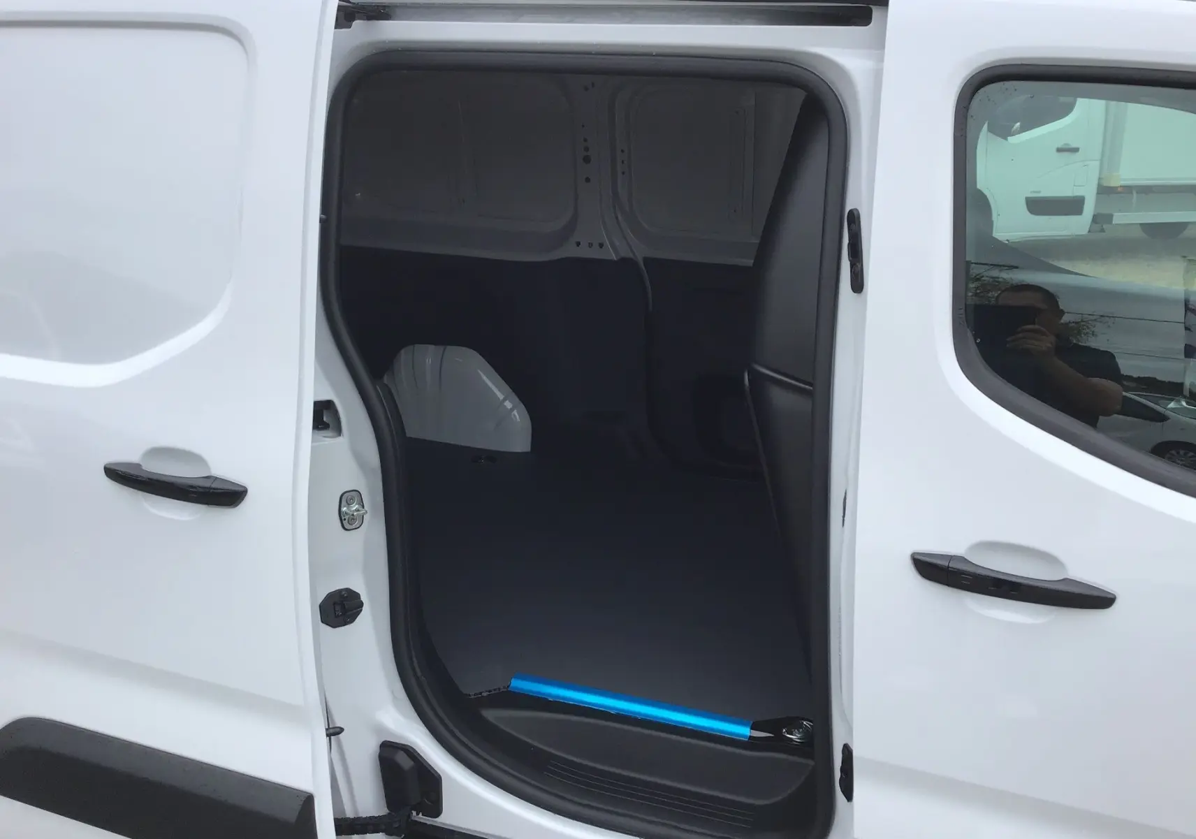 Vue latérale gauche du Peugeot Partner blanc avec porte coulissante ouverte montrant l’espace de chargement vide.