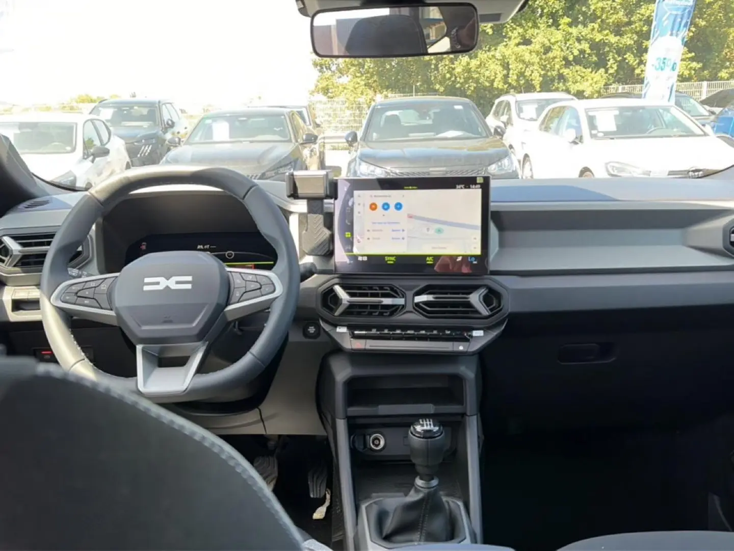 Vue intérieure avant du tableau de bord gris et volant multifonction du Dacia Bigster 2026 avec écran tactile et boîte manuelle.
