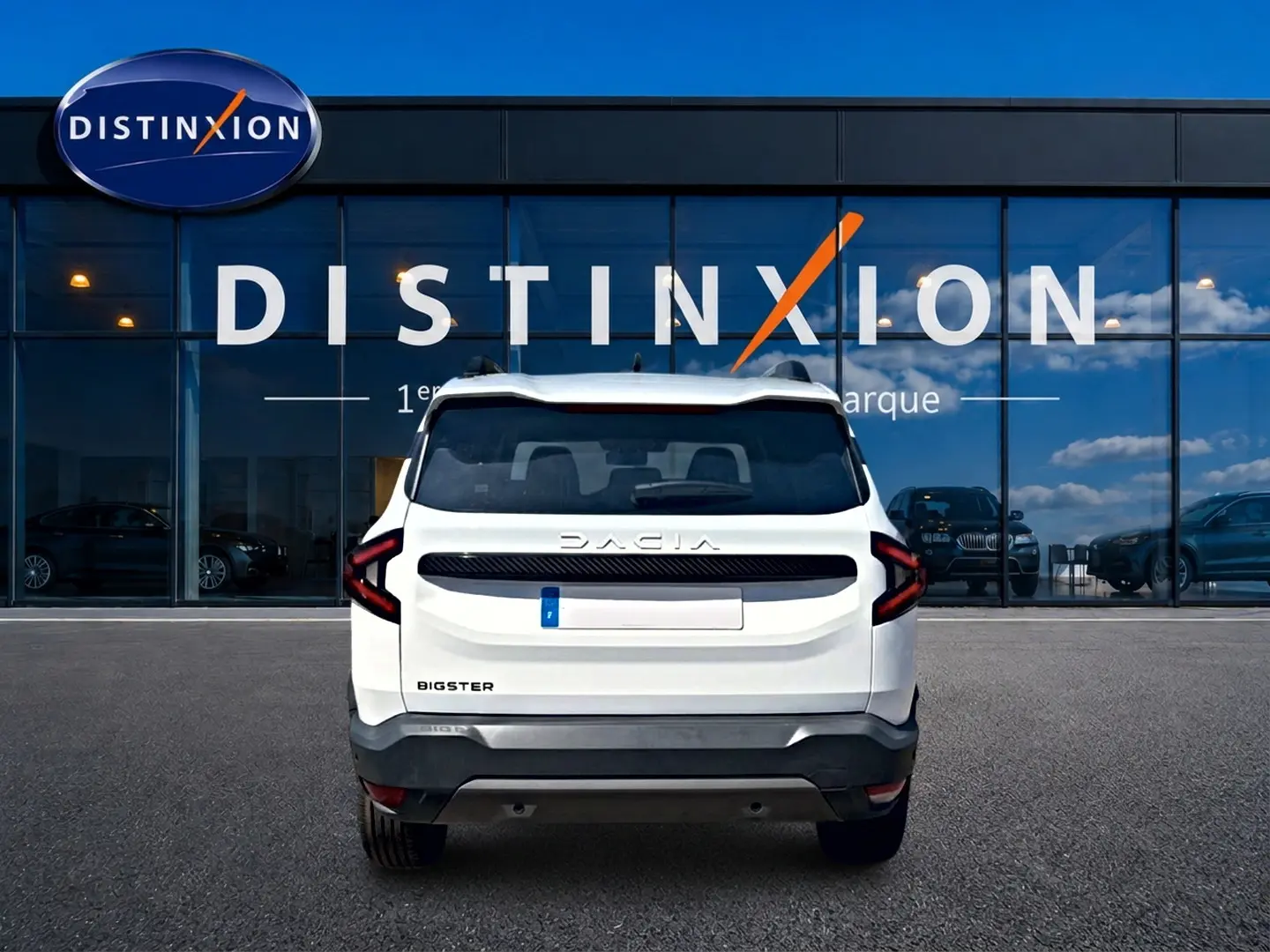 Vue arrière d'un Dacia Bigster blanc avec feux arrière LED et barres de toit, devant une vitrine Distinxion.