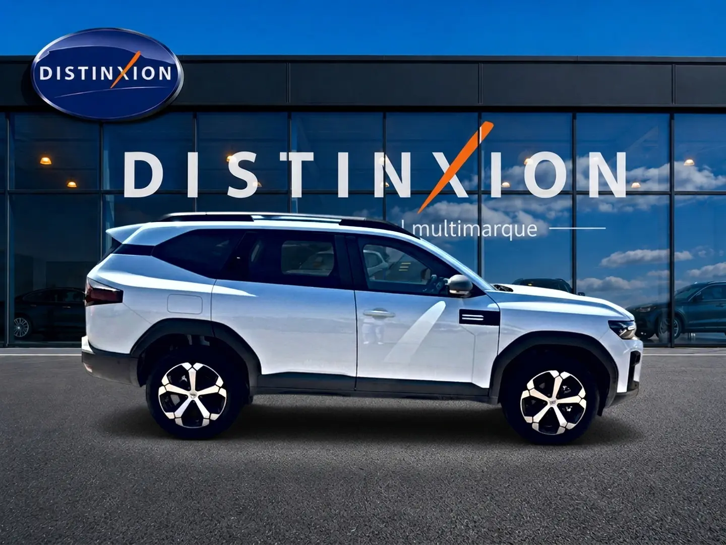 Vue latérale droite du SUV Dacia Bigster blanc 2026 avec jantes alu et barres de toit noires visibles.