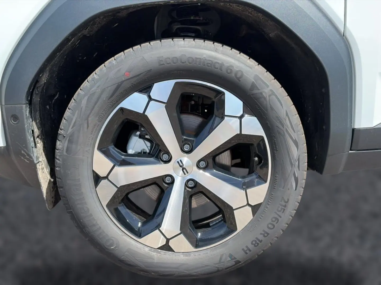 Gros plan sur la roue avant gauche du Dacia Bigster blanc, jante alliage bicolore au design hexagonal.