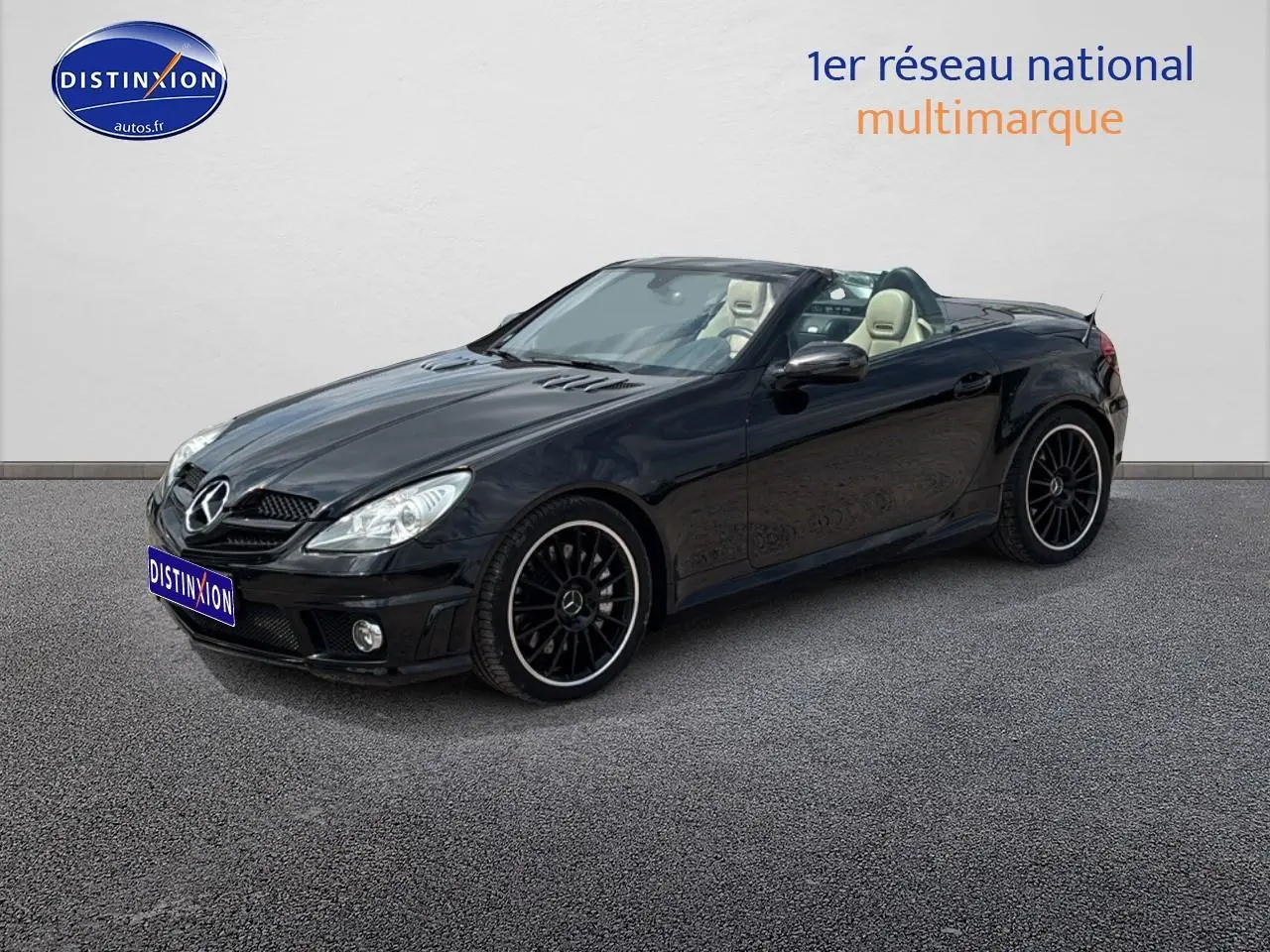 Mercedes SLK 55 AMG noir vue 3/4 avant droit, capote ouverte, jantes alu noires et intérieur cuir clair visible