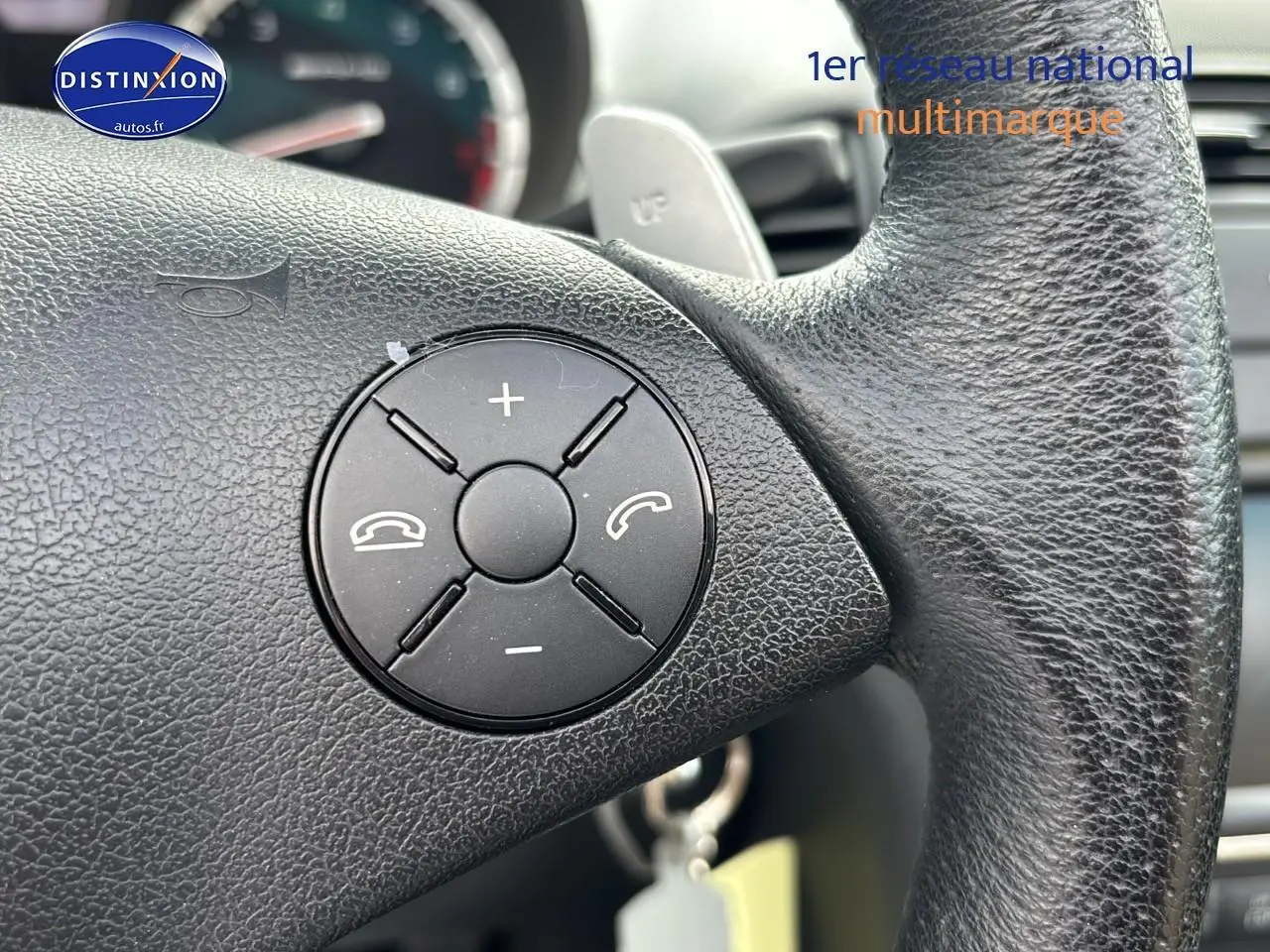 Gros plan sur le volant en cuir noir de la Mercedes SLK 55 AMG 7G-Tronic de 2009 avec commandes intégrées.