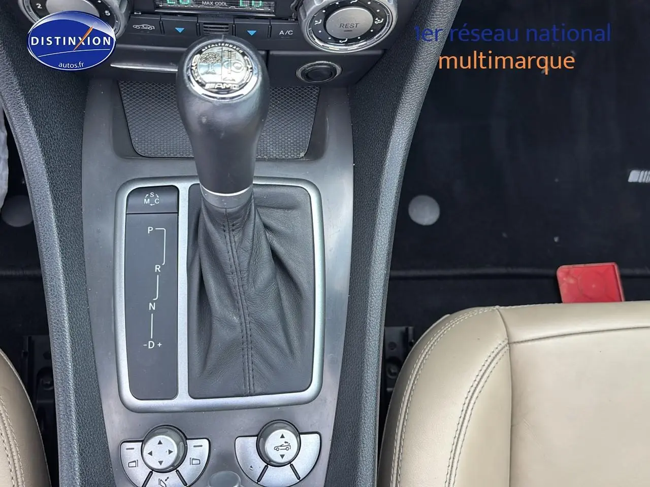 Gros plan sur la console centrale du Mercedes SLK 55 AMG noir de 2009 avec levier de vitesse automatique et sellerie cuir beige.