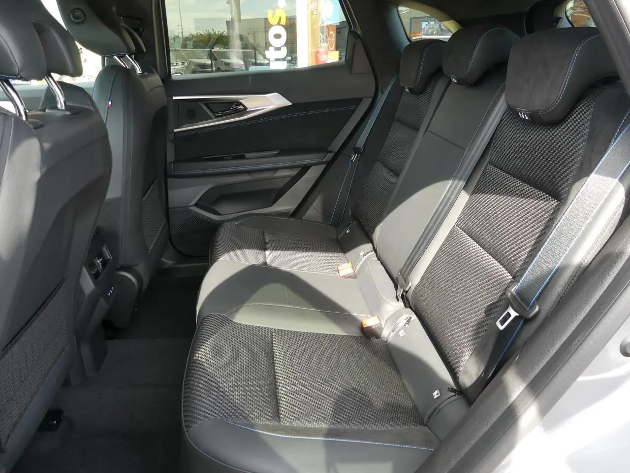 Vue latérale intérieure montrant la banquette arrière noire avec surpiqûres bleues du Renault Austral 2025 gris métallisé.