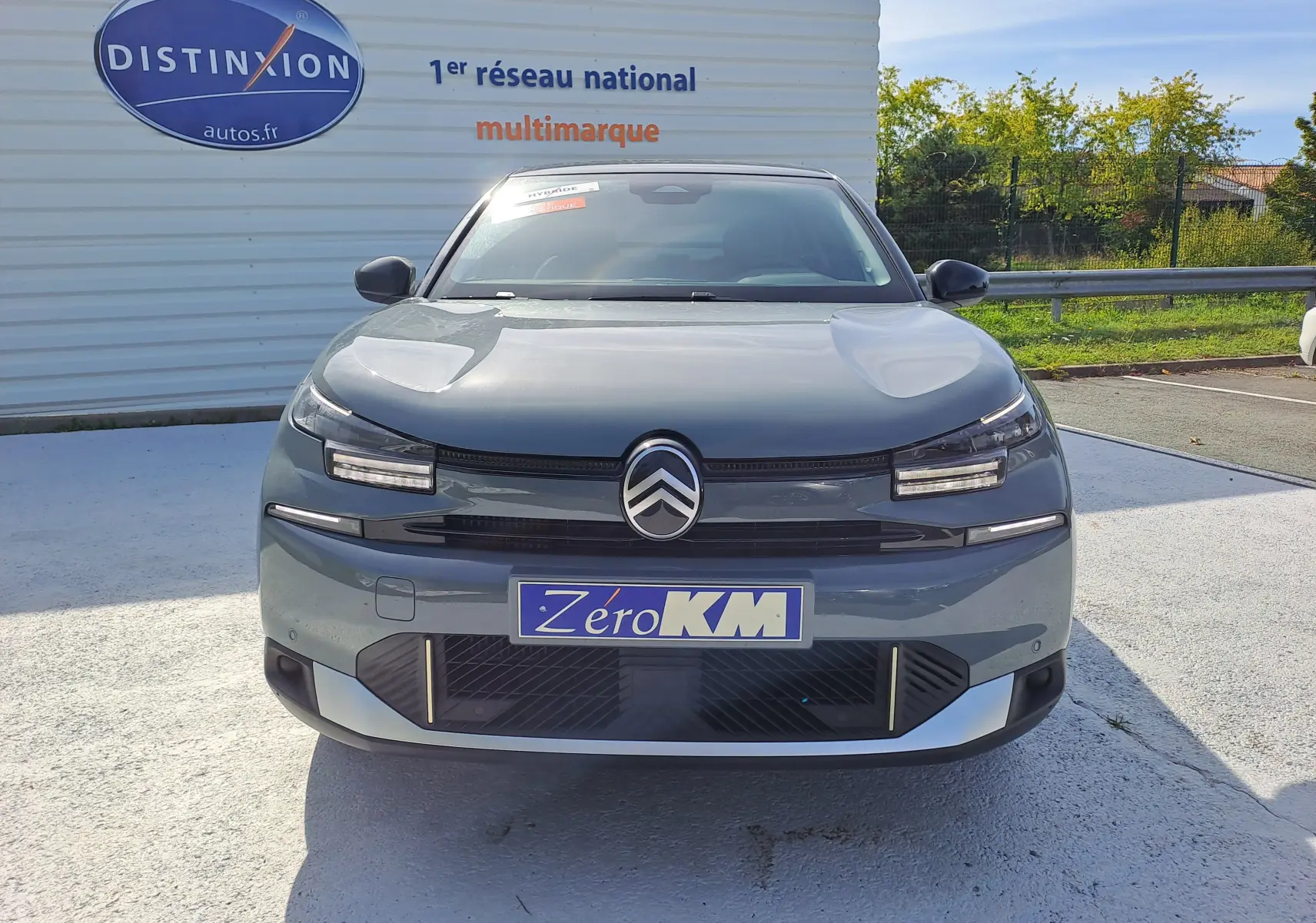 Vue frontale d'une Citroën C4 hybride 2025 en Manhattan Green avec logo distinctif et plaque Zero KM visible.