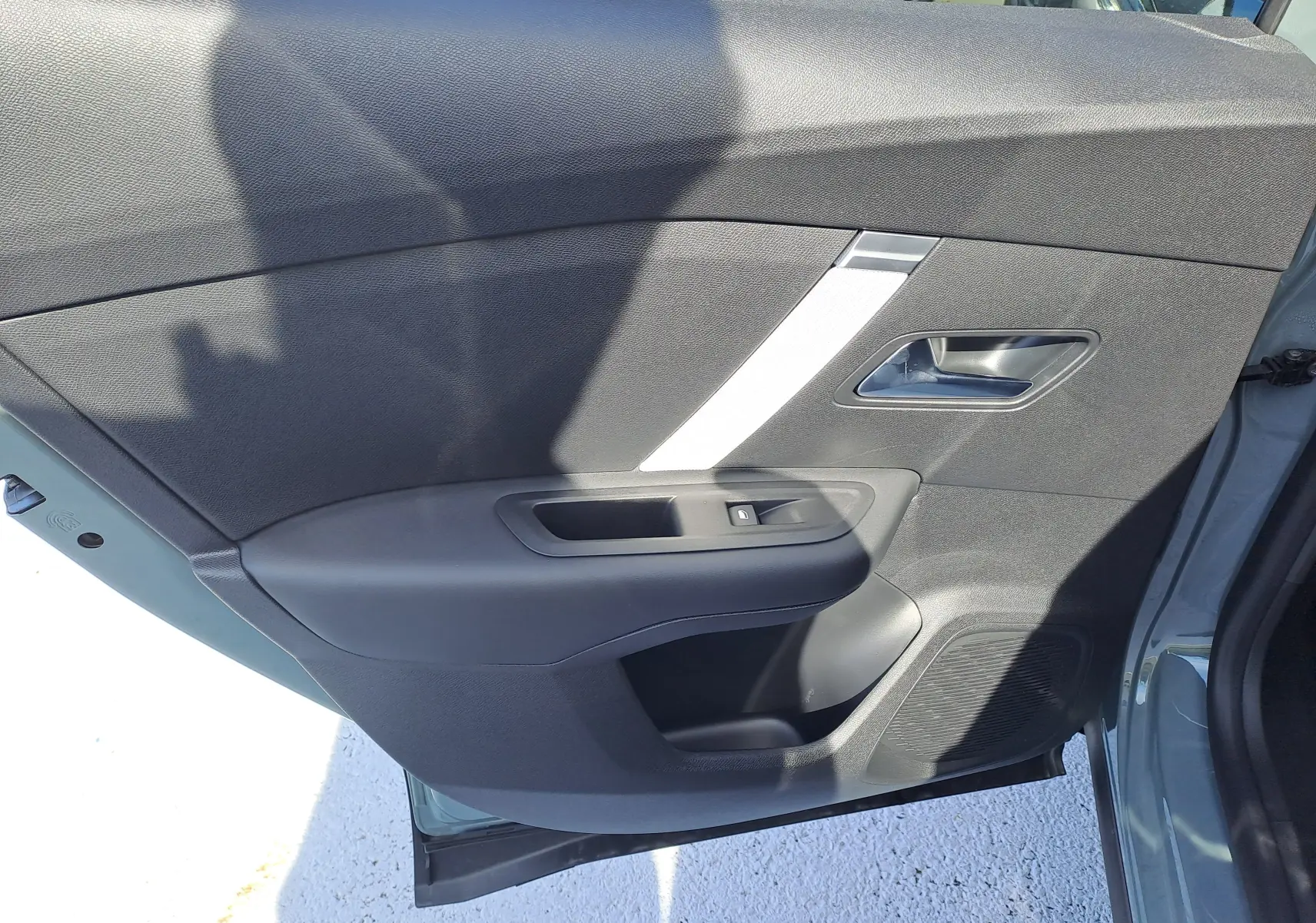 Porte arrière gauche ouverte du Citroën C4 hybride 2025 Manhattan Green, montrant le panneau intérieur noir avec poignée argentée.