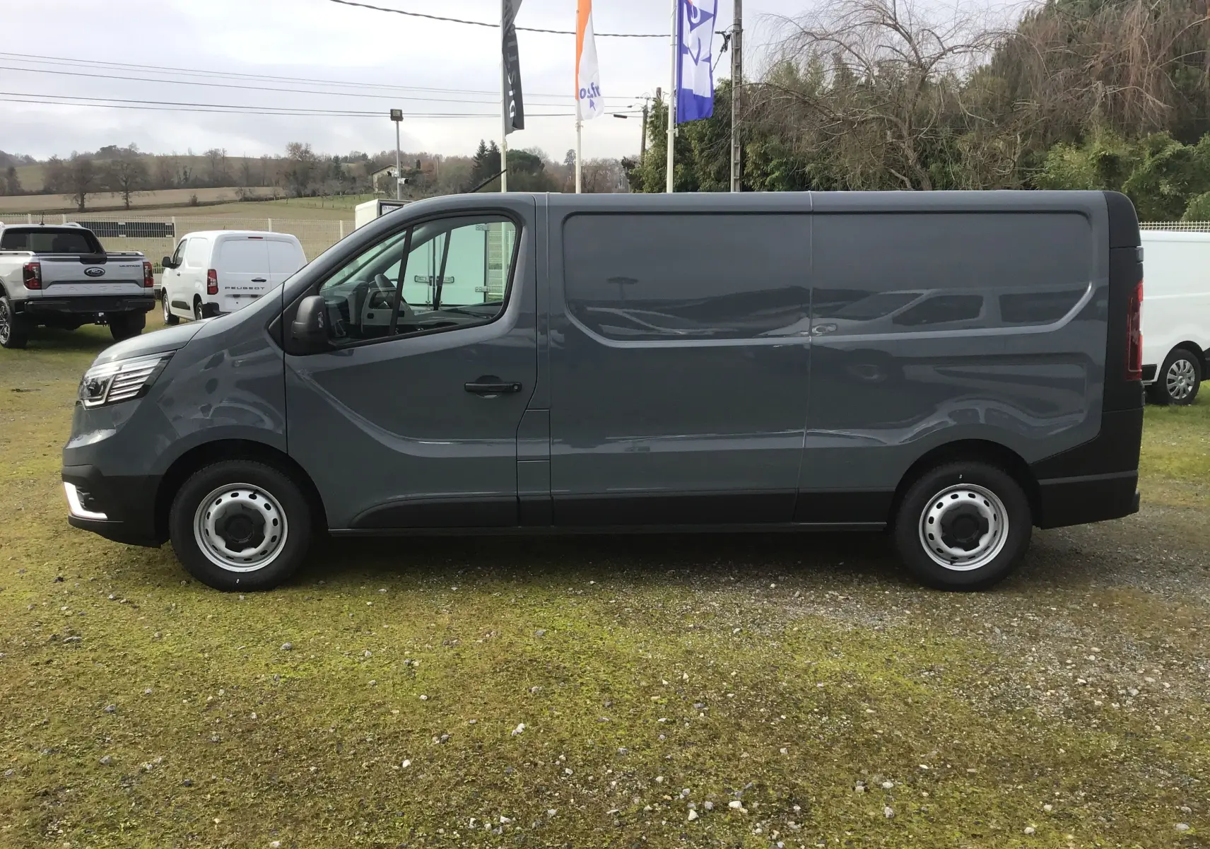 Vue de profil côté gauche du Renault Trafic Fourgon gris urbain 2025, avec porte latérale coulissante et jantes acier.