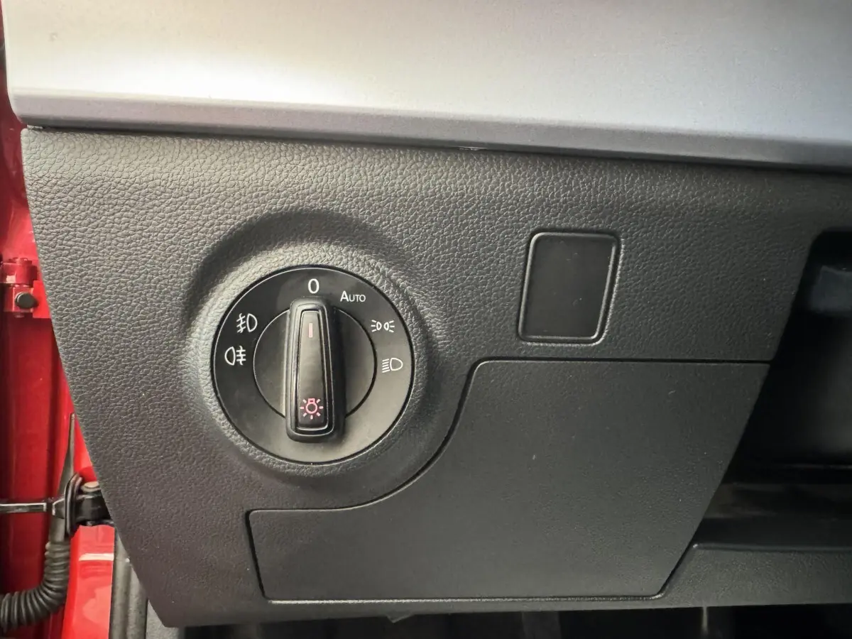 Gros plan sur le bouton de commande des phares dans l'habitacle noir d'une SEAT IBIZA rouge 2024.