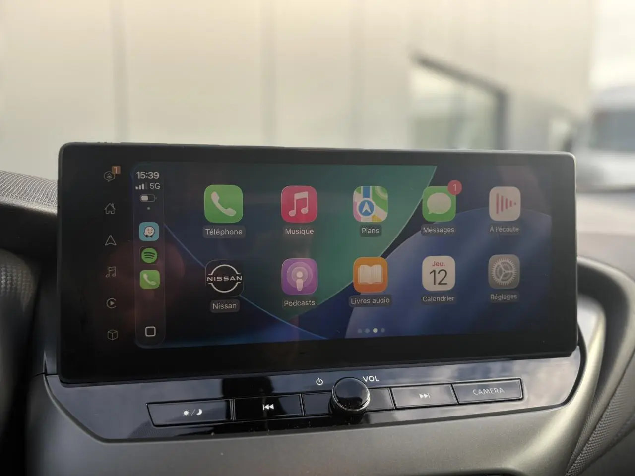 Écran tactile central affichant Apple CarPlay dans l'habitacle du Nissan Juke 2025, vue de face.
