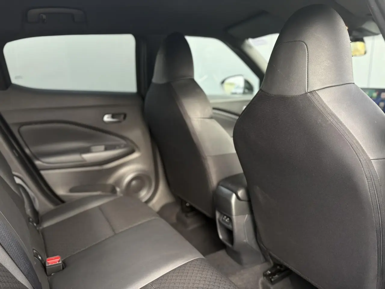 Vue intérieure arrière du Nissan Juke 2025, sièges noirs en tissu et cuir synthétique, avec port USB central visible.