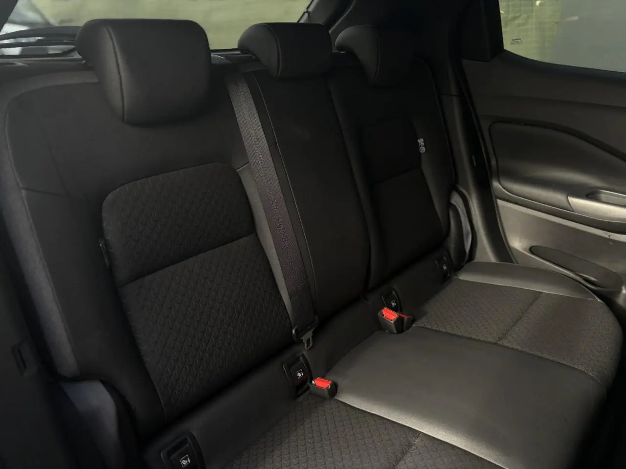 Vue latérale droite des sièges arrière noirs du Nissan Juke 2025 avec ceintures et fixations ISOFIX visibles.